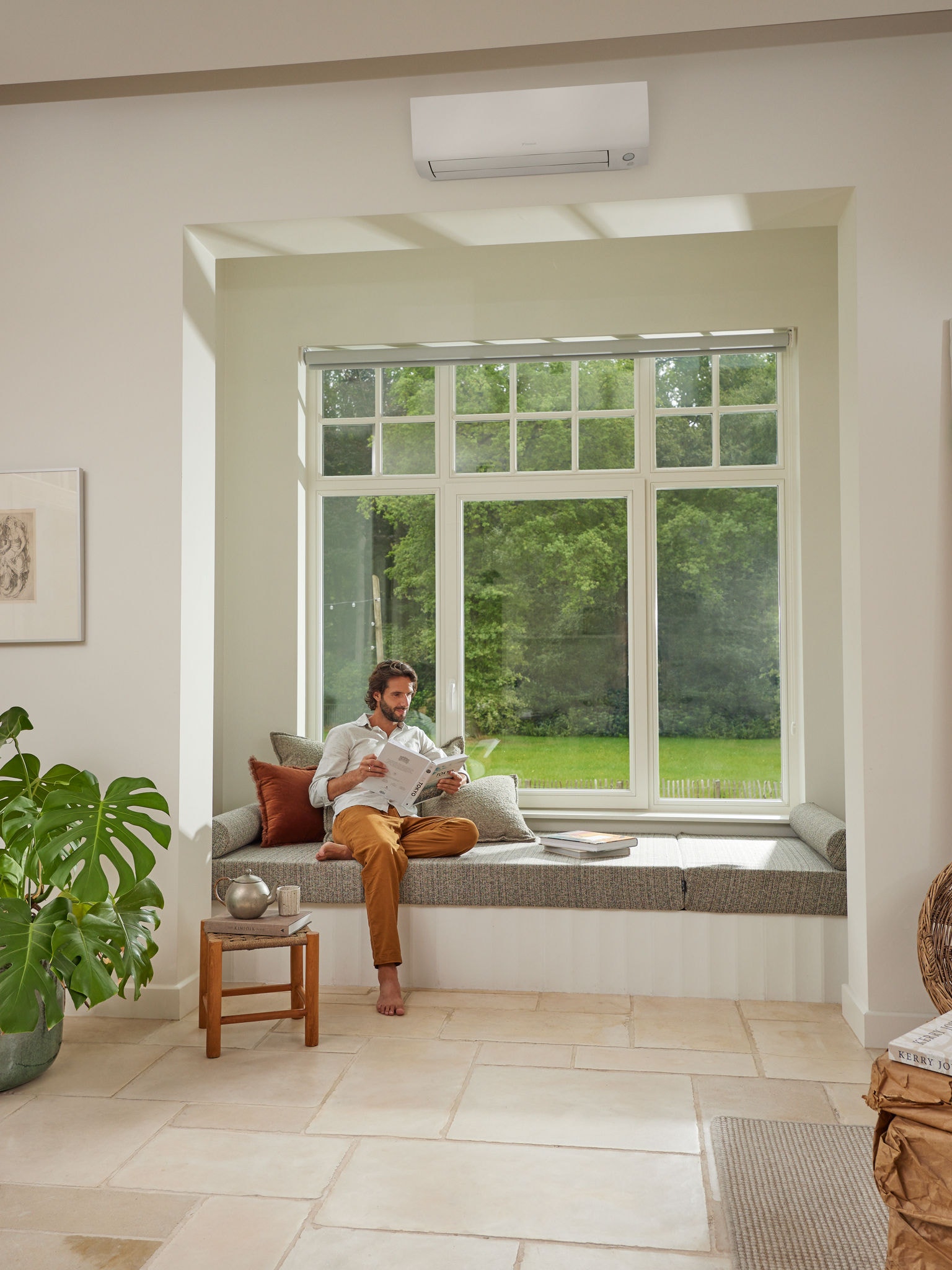 Homem a ler revista na sua sala de estar, a desfrutar de ar saudável graças à bomba de calor ar-ar Daikin que fornece ar limpo