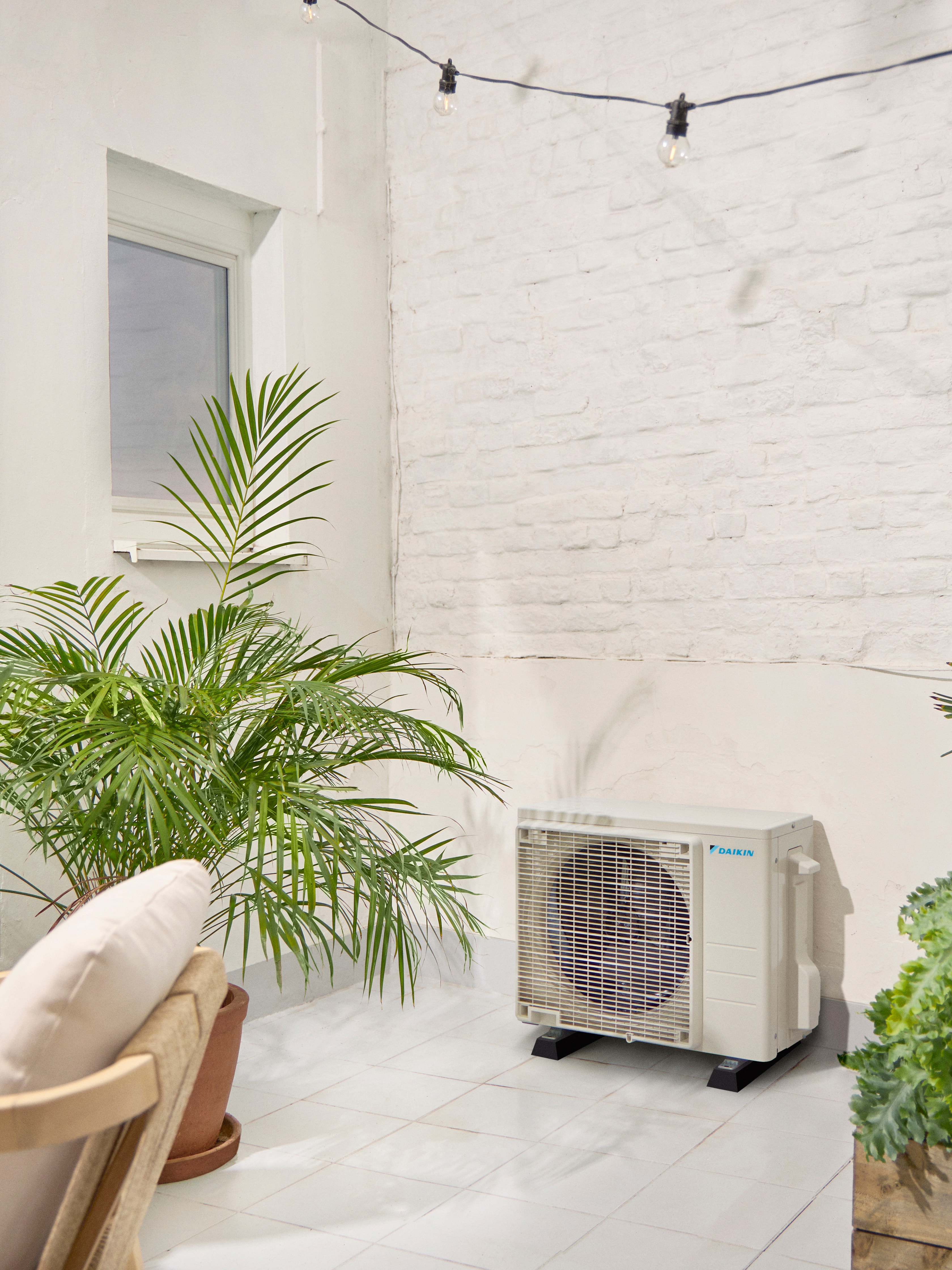 Unidade exterior Daikin num terraço branco com uma planta