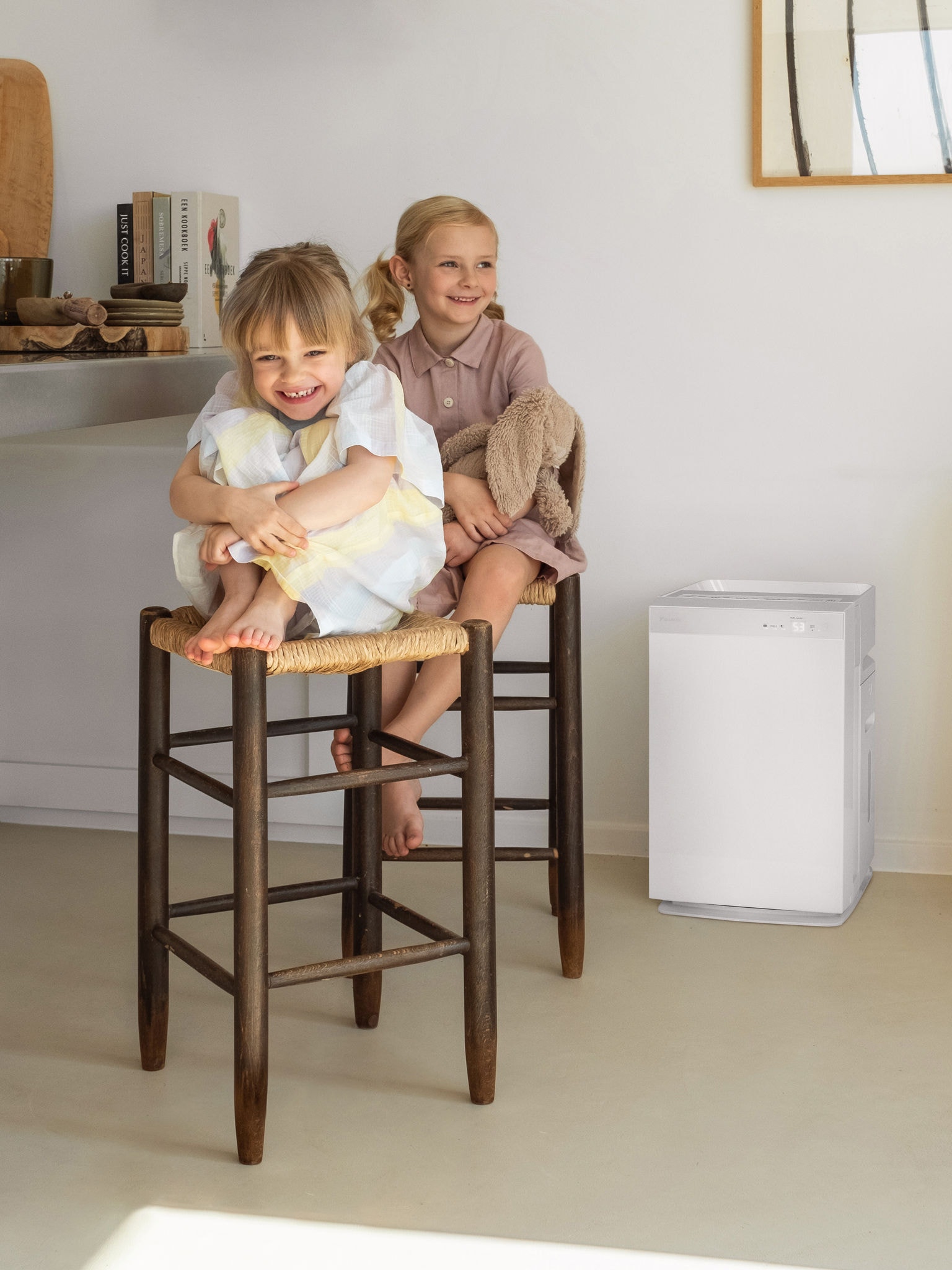 To små søstre, der sidder på taburetter i køkkenet og griner