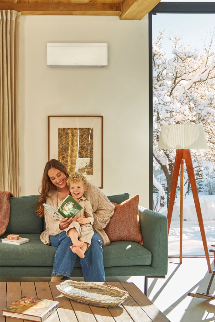 Mãe e criança a ler um livro no sofá a uma temperatura confortável